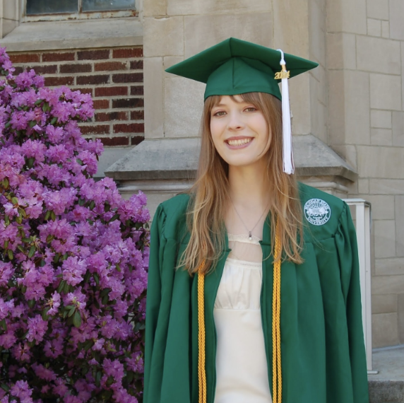 Emily Paterson, Teach Access Intern in her graduation gown. She has long hair and is smiling at the camera.