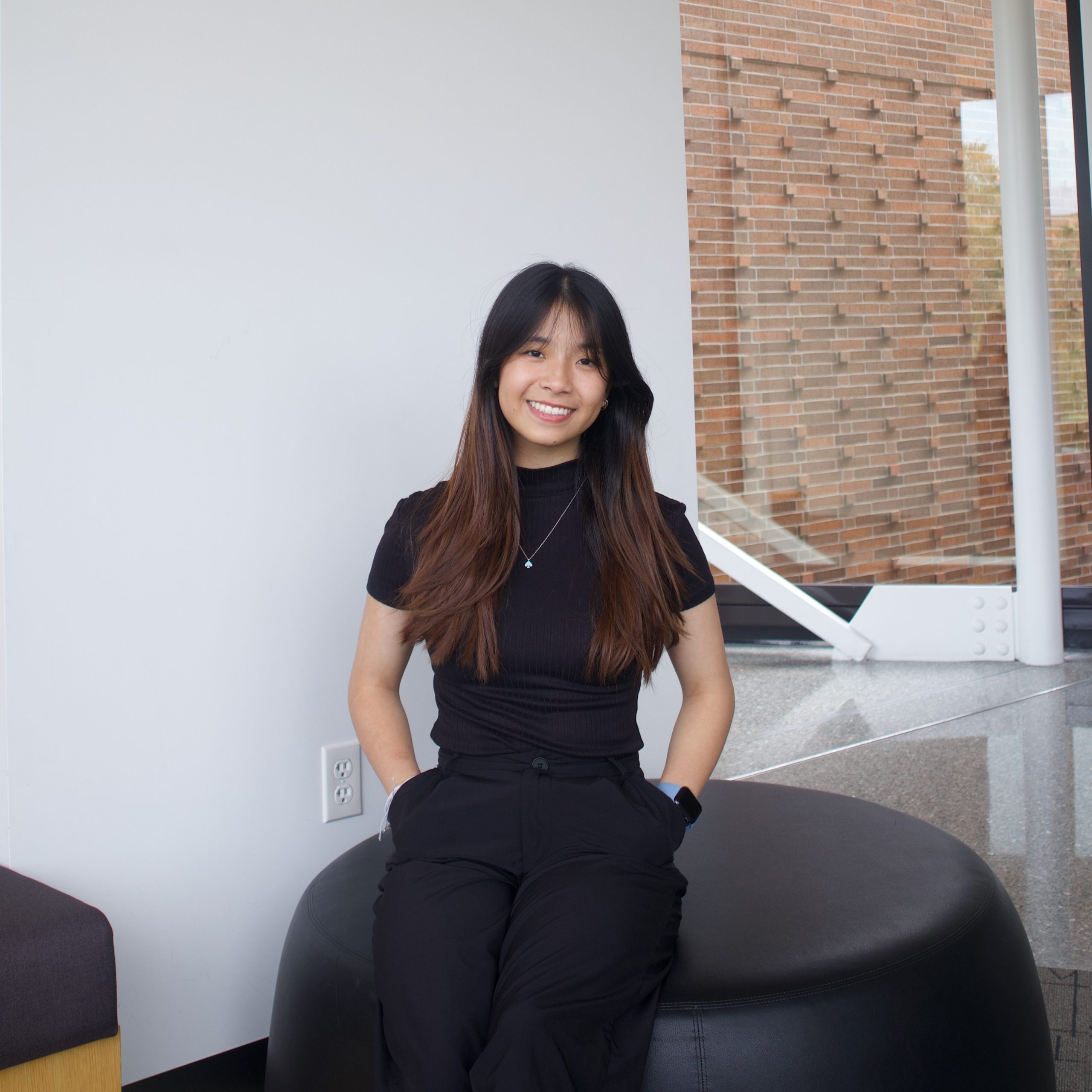 A professional headshot of Sherrye Zhong, a woman with black hair styled neatly, wearing a black top and black pants. She is smiling at the camera with a neutral background.